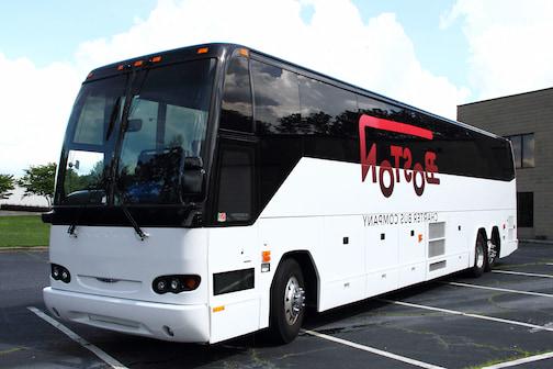 a plain white charter bus with a "Boston Charter Bus Company" logo